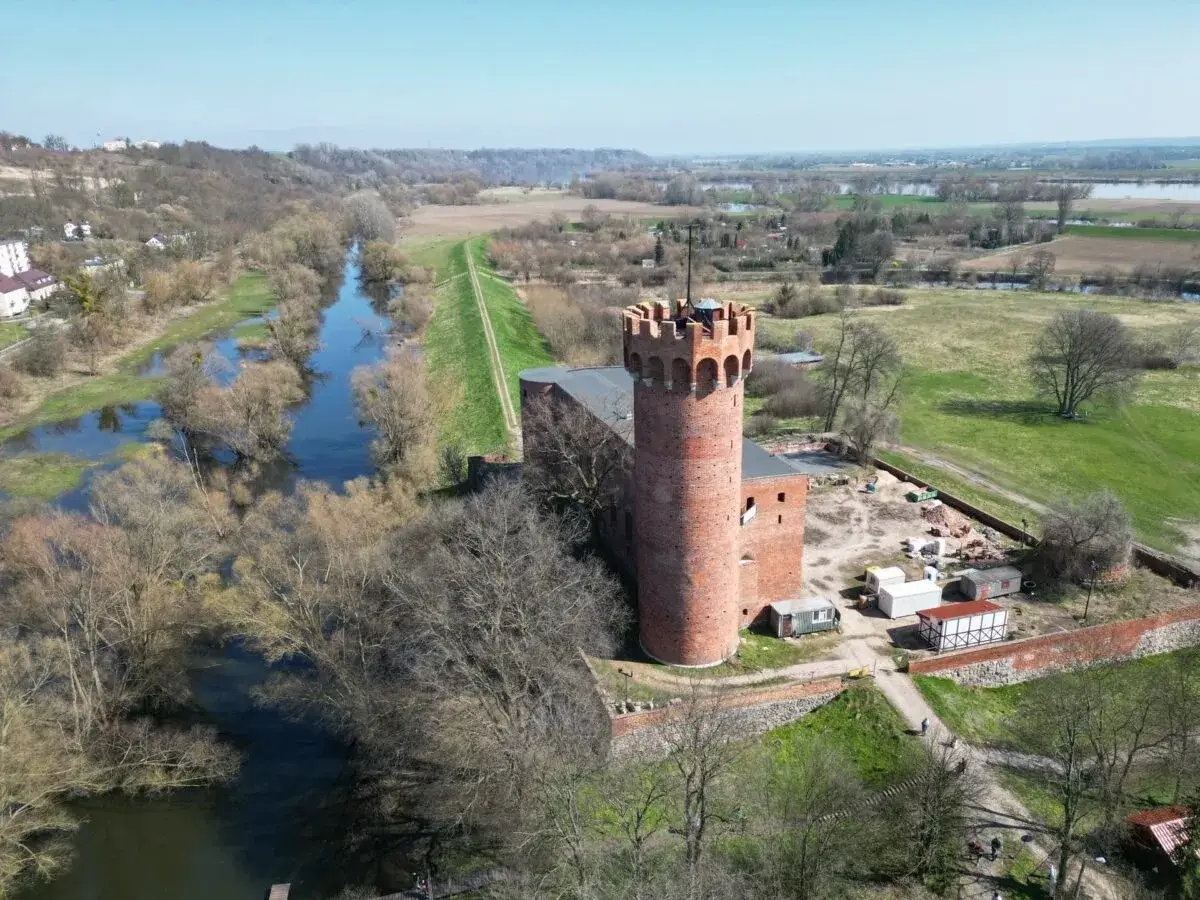 Zamek w Świeciu, ceglana wieża góruje nad otaczającym krajobrazem z rzeką i polami.