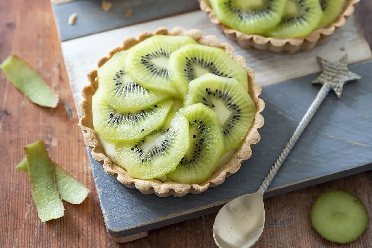 Délicieux dessert kiwi, une tartelette garnie de crème et de fines tranches de kiwi, prête à être dégustée.
