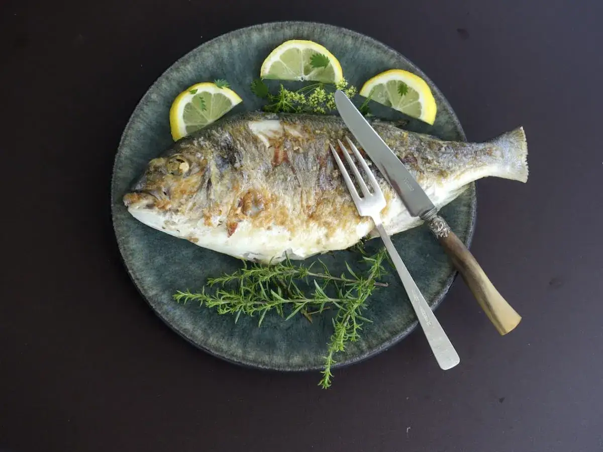 Dorade royale plancha dor&eacute;e, garnie de quartiers de citron et de romarin frais, pr&ecirc;te &agrave; &ecirc;tre d&eacute;gust&eacute;e.