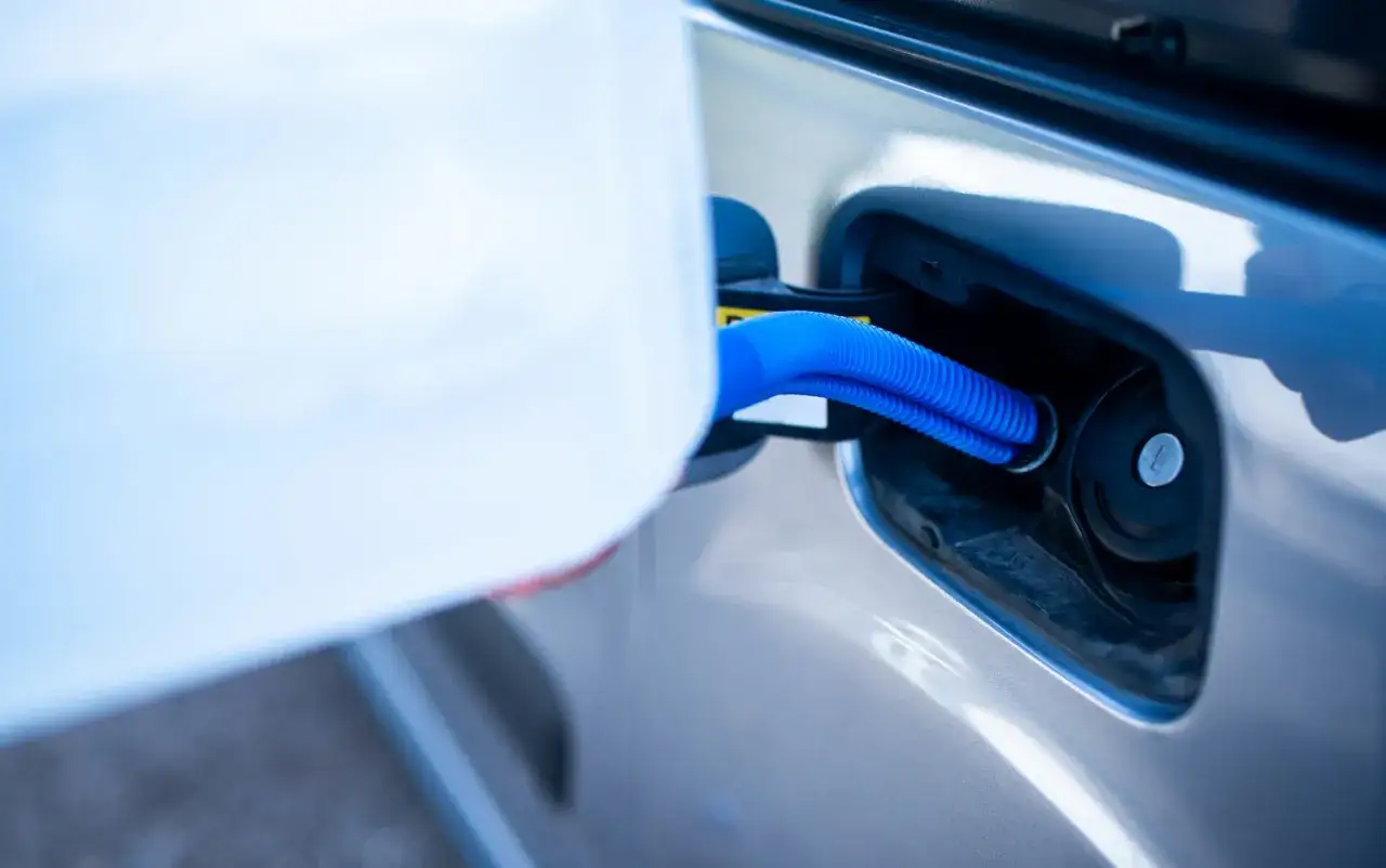 Fyller p&aring; AdBlue i bilen med en bl&aring; slang fr&aring;n en vit beh&aring;llare.