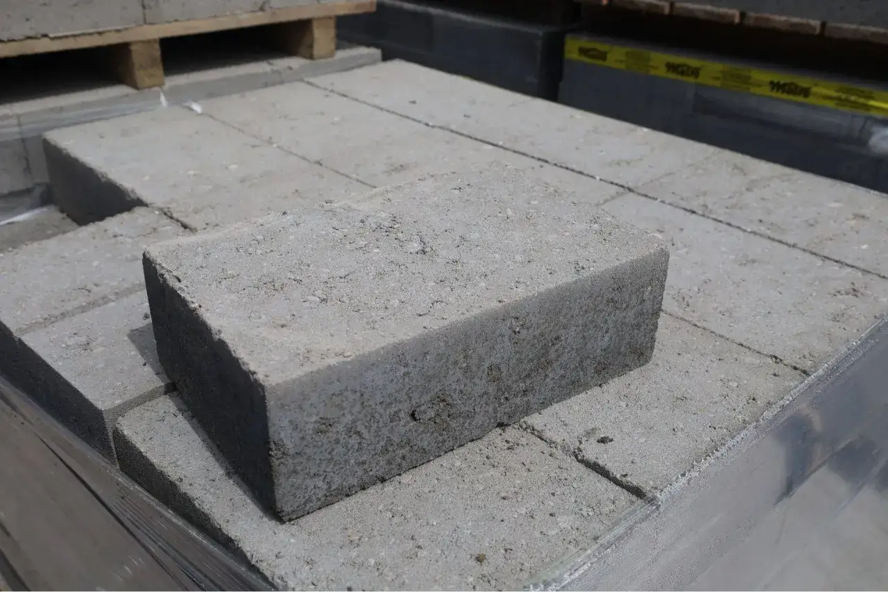 Stos szarych bloczków betonowych fundamentowych, gotowych do budowy solidnych podstaw.