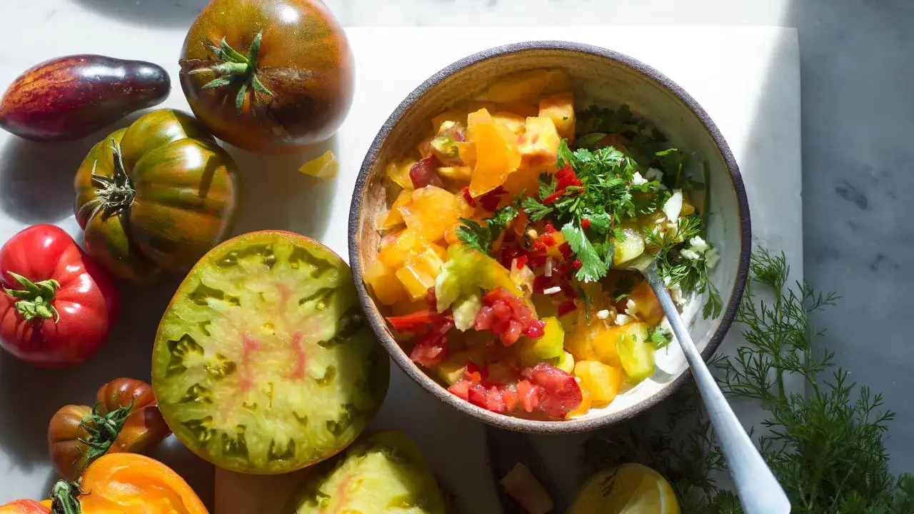 En skål med färgglad tomatsalsa, perfekt för ett enkelt tomatsalsa recept. Omgiven av olika sorters tomater.