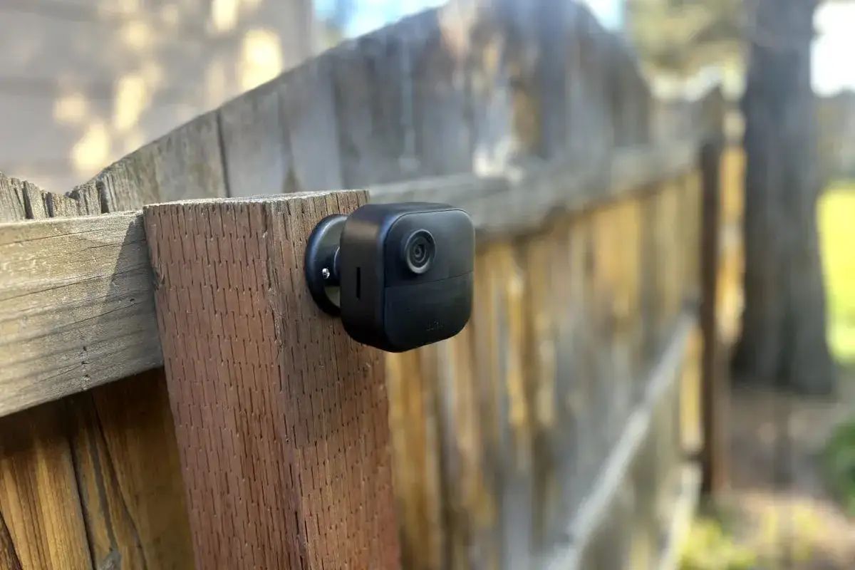 Installation d'une cam&eacute;ra de surveillance discr&egrave;te sur une cl&ocirc;ture en bois pour une s&eacute;curit&eacute; accrue.