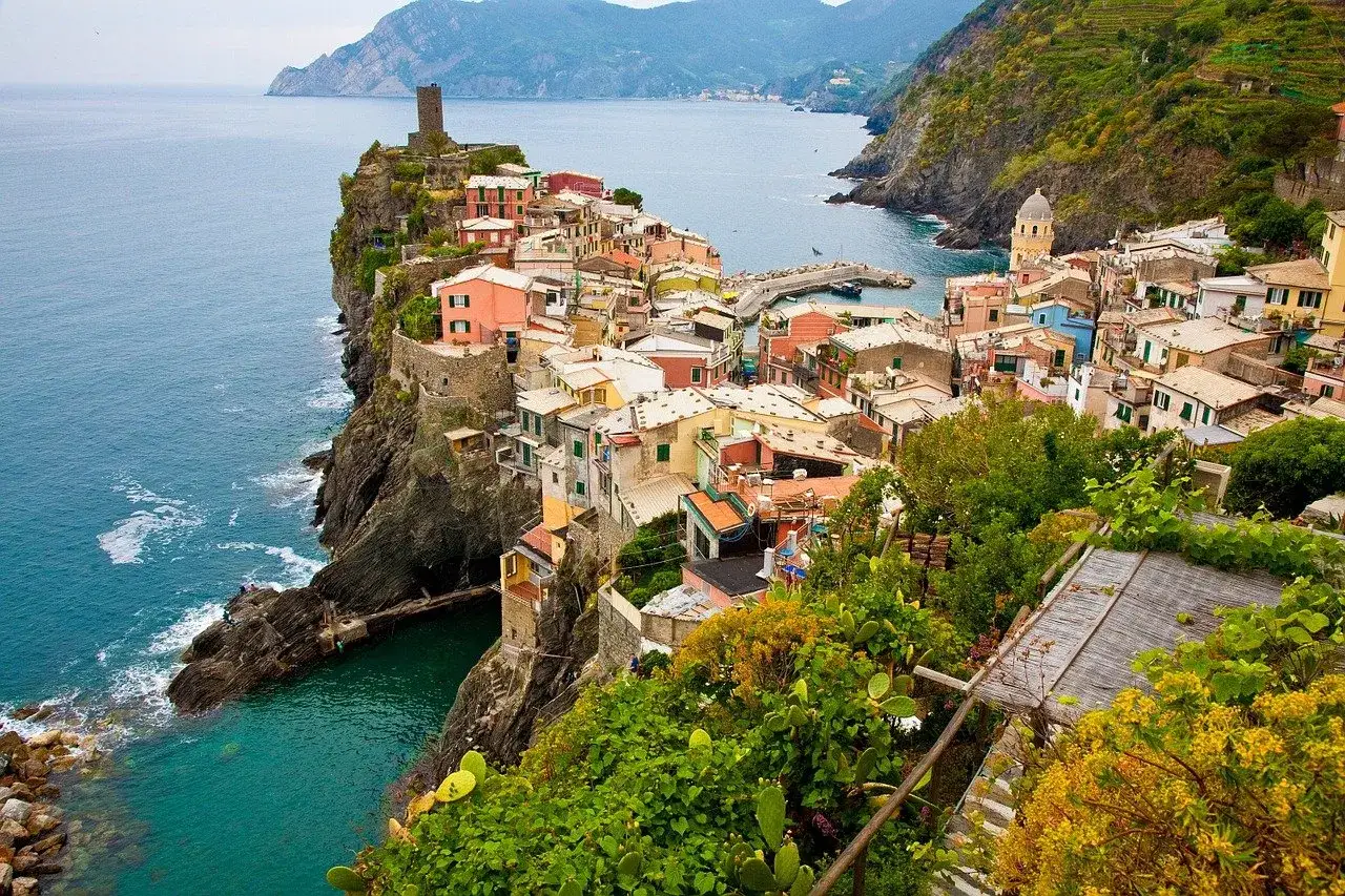Kolorowe domy Cinque Terre na klifie nad turkusowym morzem. Marzysz o tanich lotach do Włoch? To idealne miejsce!
