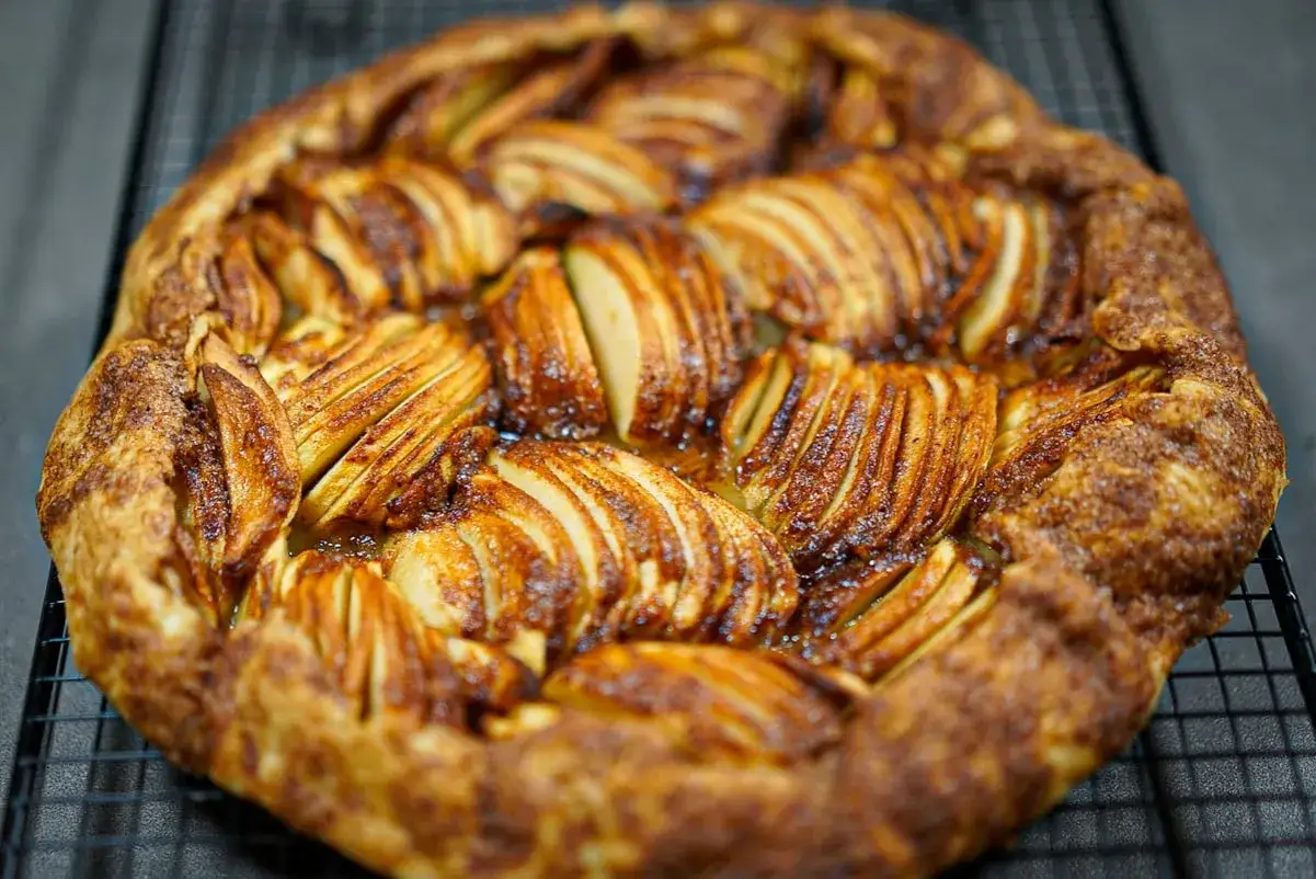 Tarte aux pommes à l'ancienne, ses fines tranches de pommes caramélisées et sa pâte dorée invitent à la gourmandise.