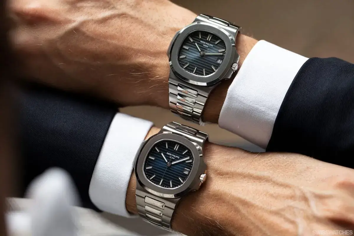Dos relojes Patek Philippe, uno encima del otro, en muñecas con trajes elegantes. Un duelo de alta relojería: ¿Audemars Piguet vs Patek Philippe?