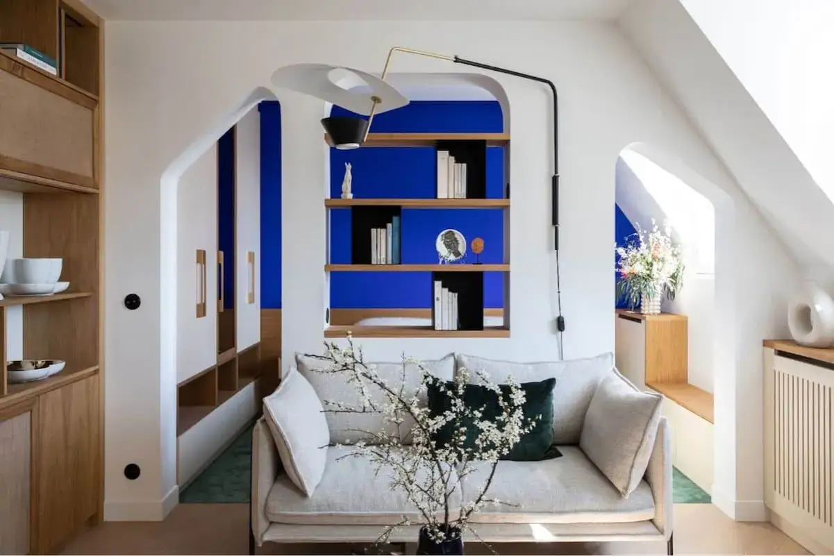 Salon moderne avec canapé clair, étagères en bois et murs d'un bleu klein et bleu majorelle saisissant.