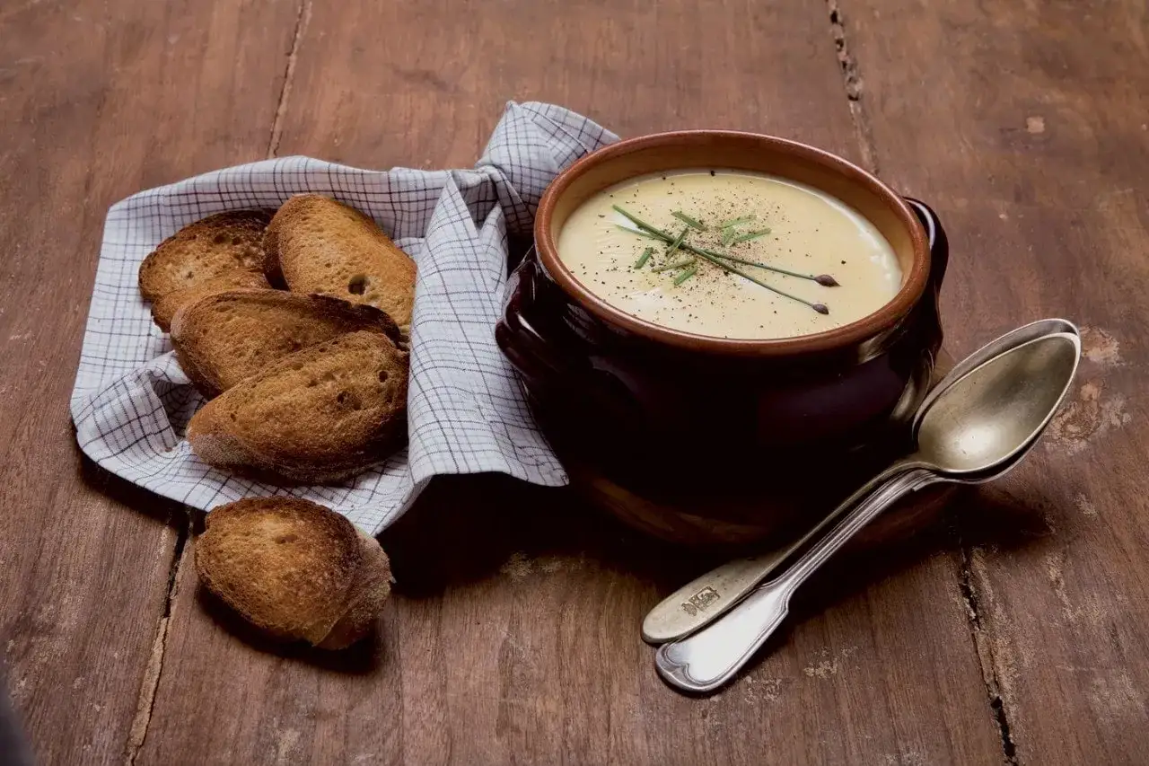 Una cremosa fonduta, perfetta per una ricetta confortante, servita con crostini dorati su un tavolo di legno rustico.