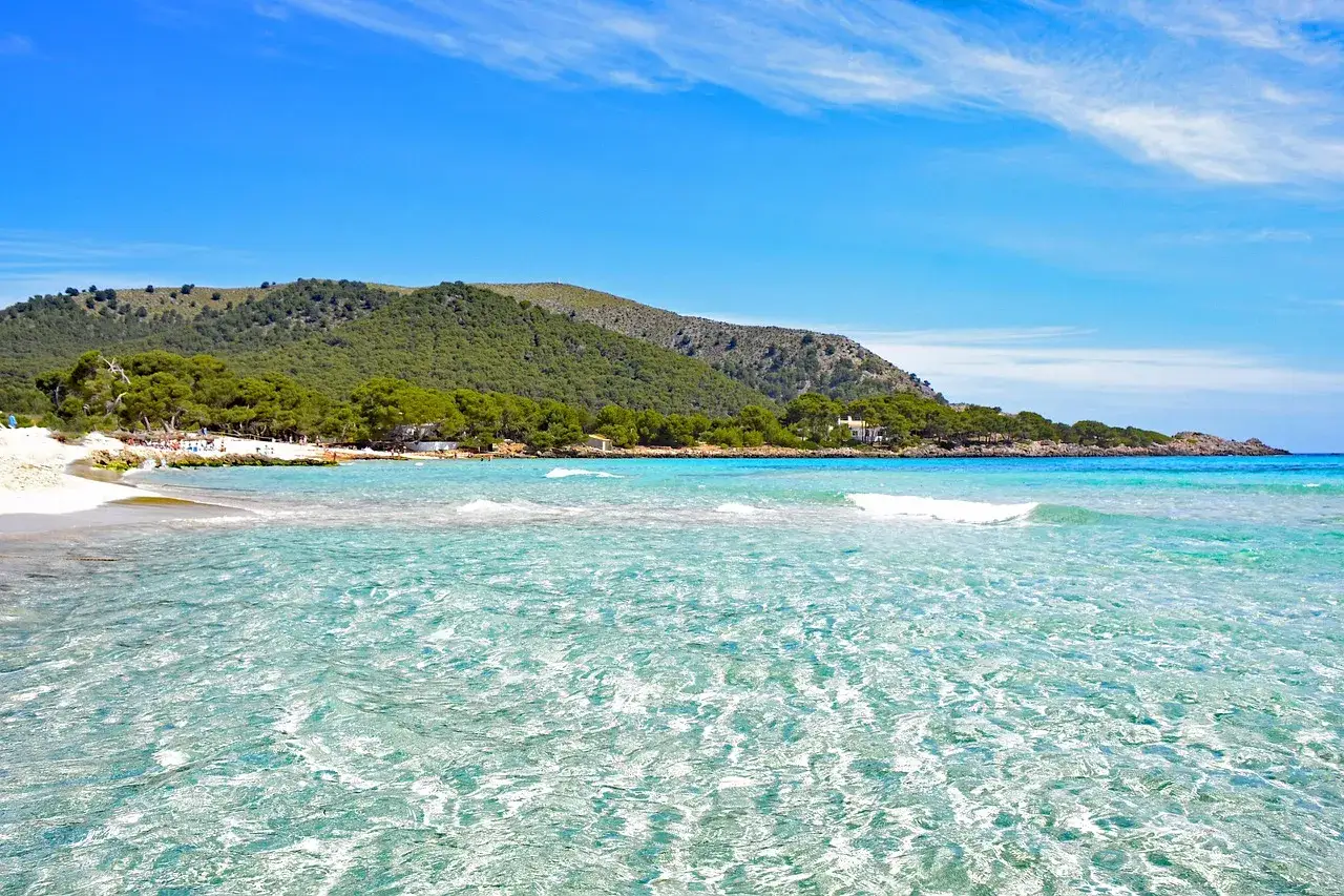 Cala Agulla: turkusowa woda, piaszczysta plaża i zielone wzgórza tworzą idylliczny krajobraz.