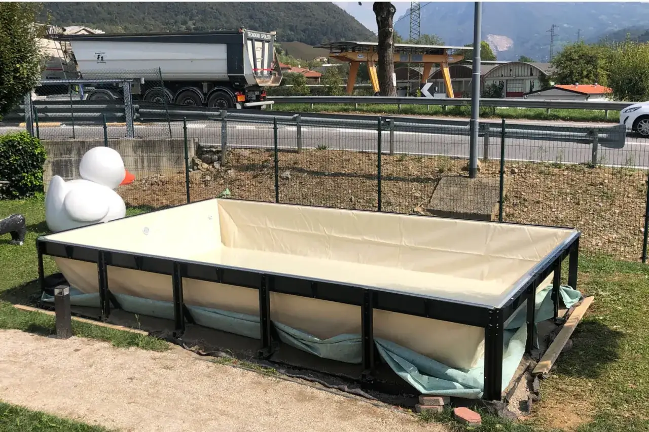 Piscina seminterrata in fase di installazione, con un grande anatra gonfiabile sullo sfondo. Si attendono i permessi per completare il progetto.