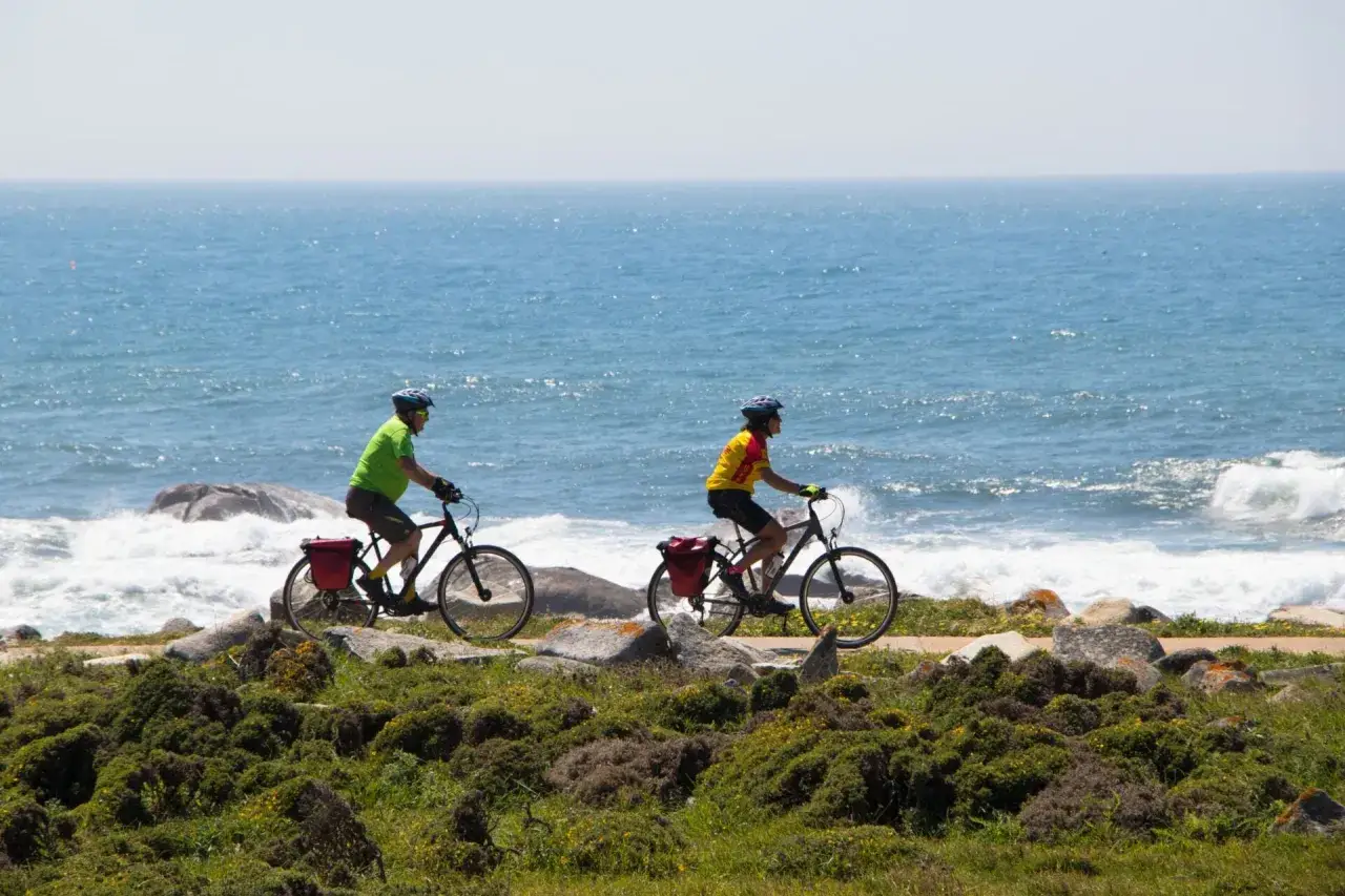 Zwei Radfahrer auf dem Jakobsweg mit Fahrrad, genie&szlig;en die K&uuml;stenlandschaft und das Meer.