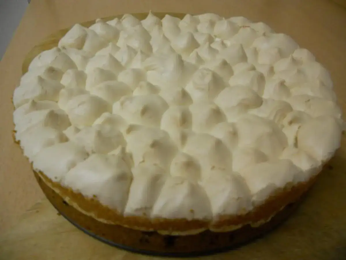 Ein runder Johannisbeer Baiser Kuchen mit einer fluffigen Baisermasse, die wie kleine Wolken aussieht.