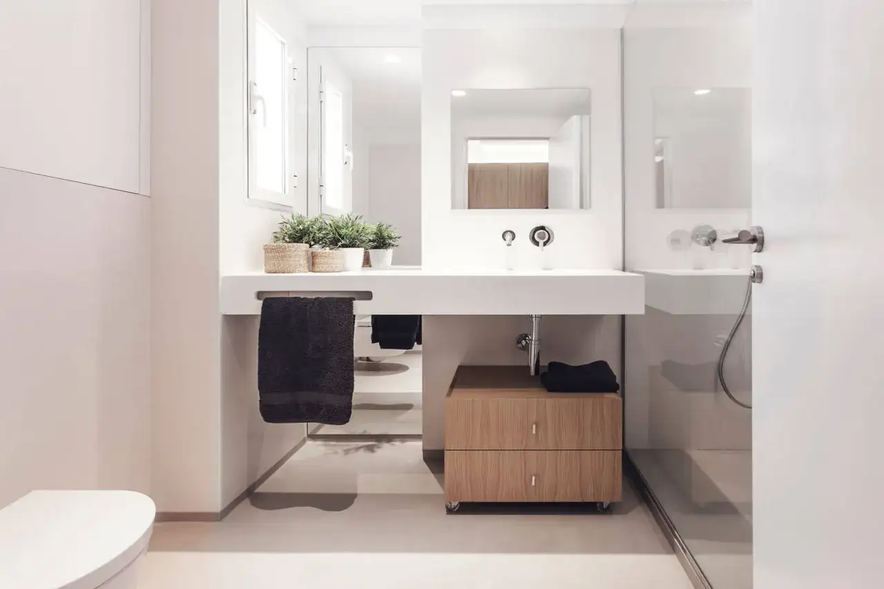 Ba&ntilde;o moderno con lavabo flotante, plantas y toallero. Un mueble de madera con ruedas bajo el lavabo es ideal para tu presupuesto de reforma de ba&ntilde;o.