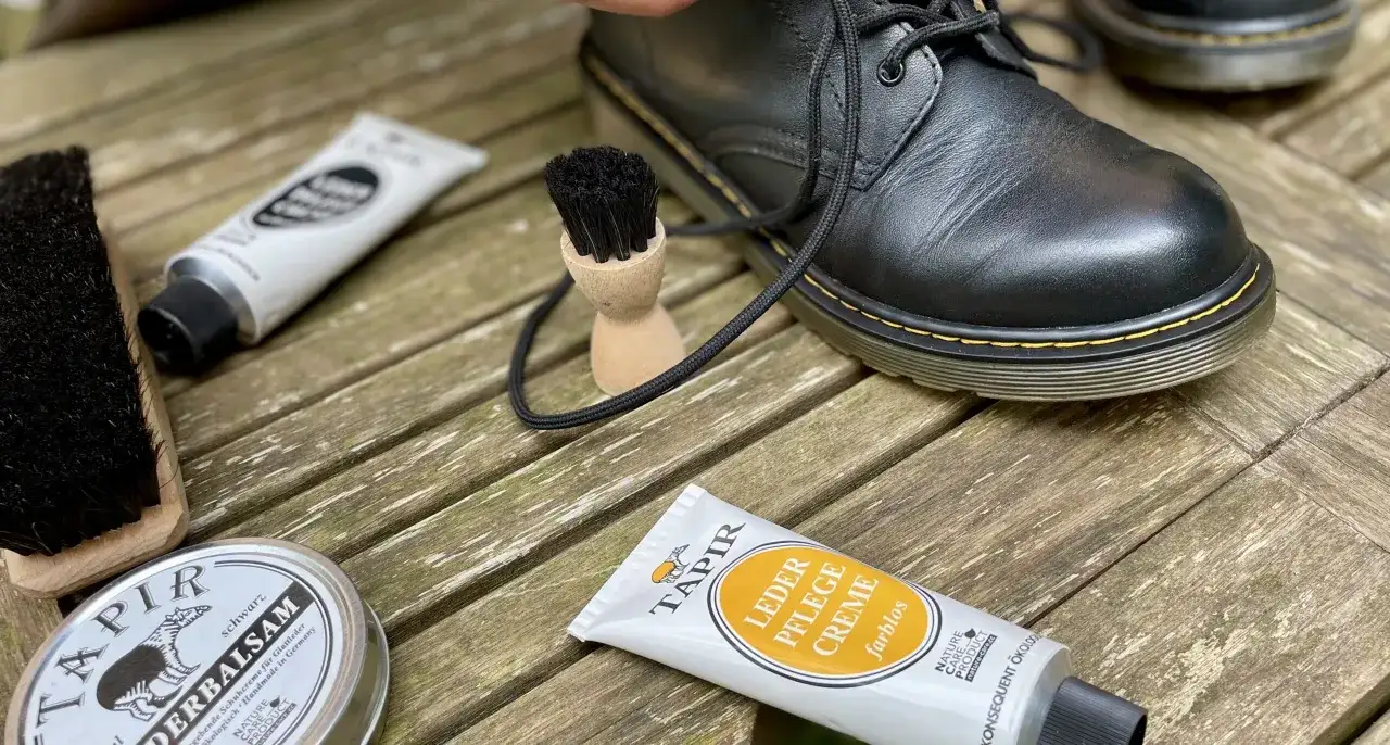 Schwarze Lederstiefel werden mit Tapir Lederpflegecreme und Bürsten gepflegt. Glattleder pflegen ist wichtig für Langlebigkeit.