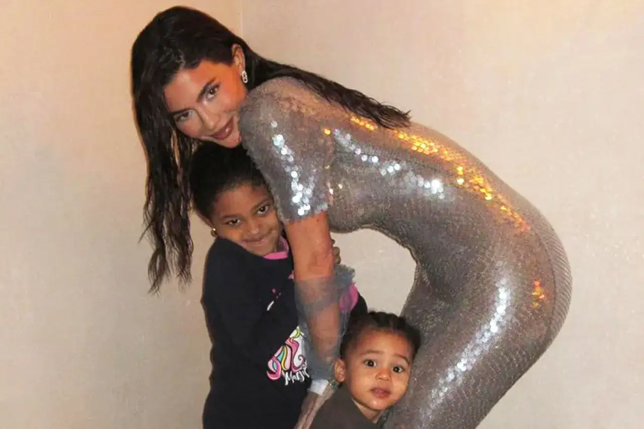 Kylie Jenner w błyszczącej sukience przytula swoje dzieci.