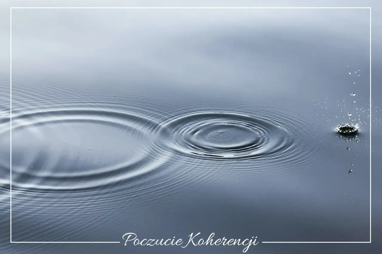 Kropla wody spada na spokojną taflę, tworząc kręgi. To obraz poczucia koherencji, gdzie każdy element harmonijnie wsp&oacute;łgra.