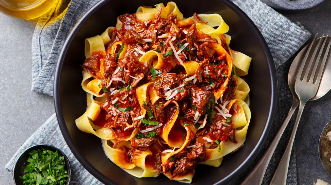 Pappardelle, czyli makaron długi płaski, polany gęstym, aromatycznym ragu z wołowiny, posypany parmezanem i natką pietruszki.