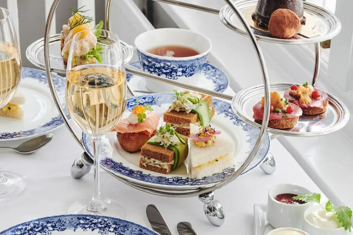 En elegant afternoon tea med små smörgåsar, bakverk och bubbel. Perfekt för en lyxig fika eller som inspiration för ett eget afternoon tea recept.