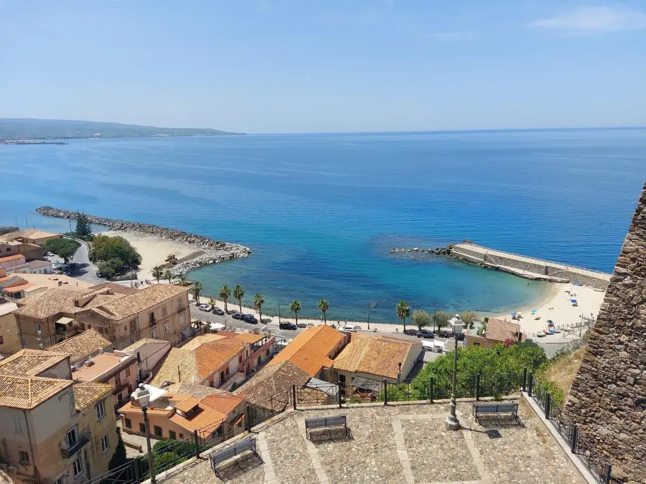 Vista panoramica di un villaggio costiero in Calabria, con case dai tetti arancioni e un mare azzurro cristallino. Un invito a esplorare la **Calabria coast to coast**.