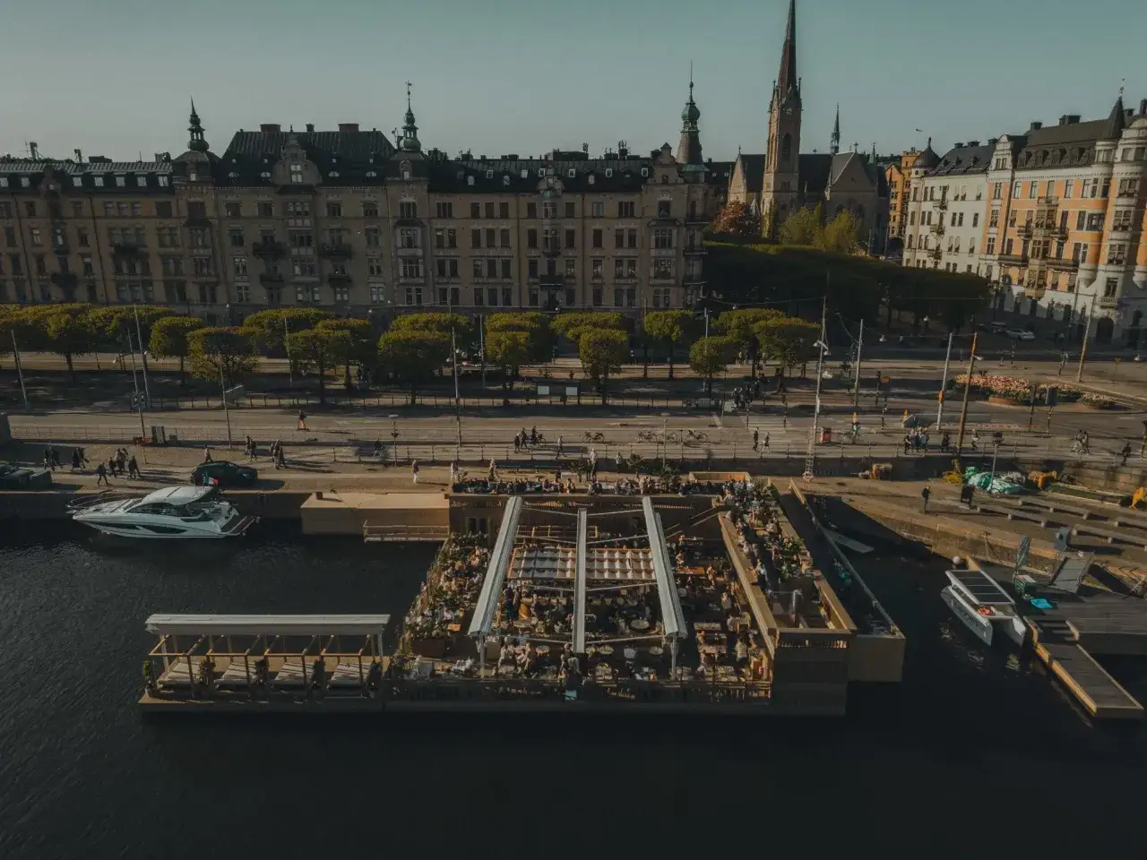 En livlig restaurang vid vattnet i Stockholm, med folk som njuter av solen på en flytande terrass.