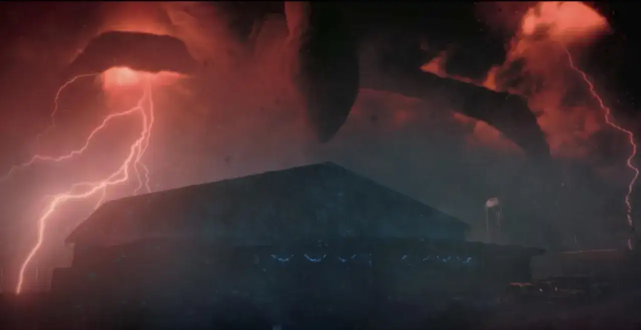 Le ciel rougeoyant de Stranger Things saison 6 date de sortie, avec des éclairs et une créature menaçante au-dessus d'un bâtiment.