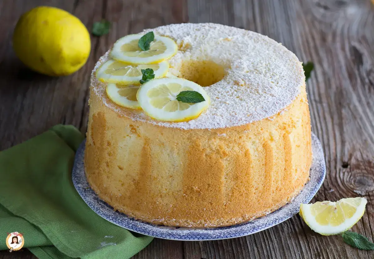 Delizioso chiffon cake al limone, spolverato di zucchero a velo e decorato con fette di limone fresco e menta.