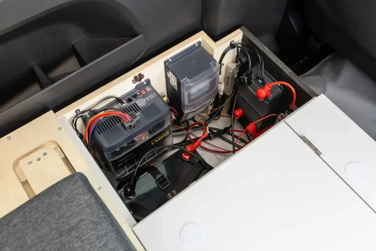 Syst&egrave;me de chauffage pour van sans &eacute;lectricit&eacute; : batteries, c&acirc;blage et bo&icirc;tier de commande install&eacute;s dans un compartiment am&eacute;nag&eacute;.