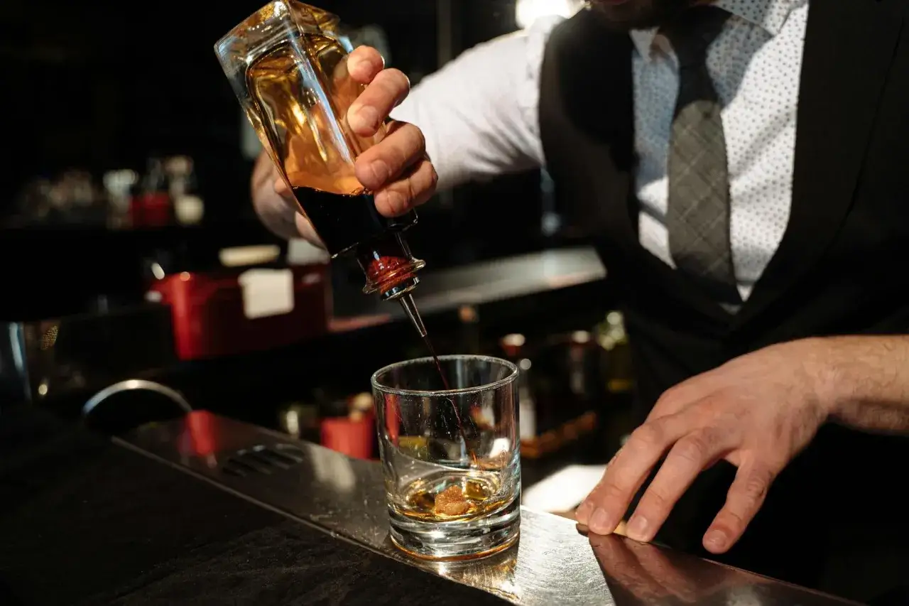 Barman dodaje składnik do szklanki. Zbyt długie mieszanie drinków typu stirred może prowadzić do mętnienia.