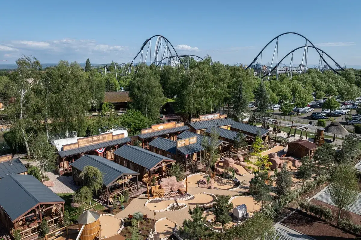 Western miasteczko w parku rozrywki, z kolejkami górskimi w tle. To największy park rozrywki w Europie, oferujący mnóstwo atrakcji.
