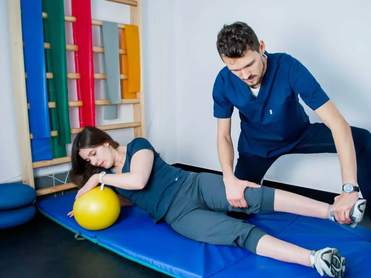 Fizjoterapeuta pomaga pacjentce w ćwiczeniach z piłką. PNF fizjoterapia to metoda rehabilitacji.