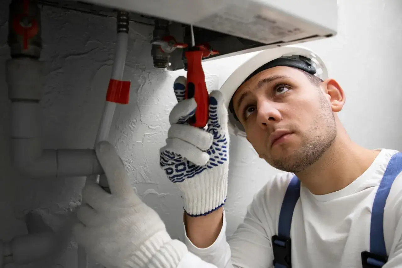 Serwisant w białej rękawicy naprawia instalację, gdy Vaillant piec gazowy dwufunkcyjny nie grzeje wody.