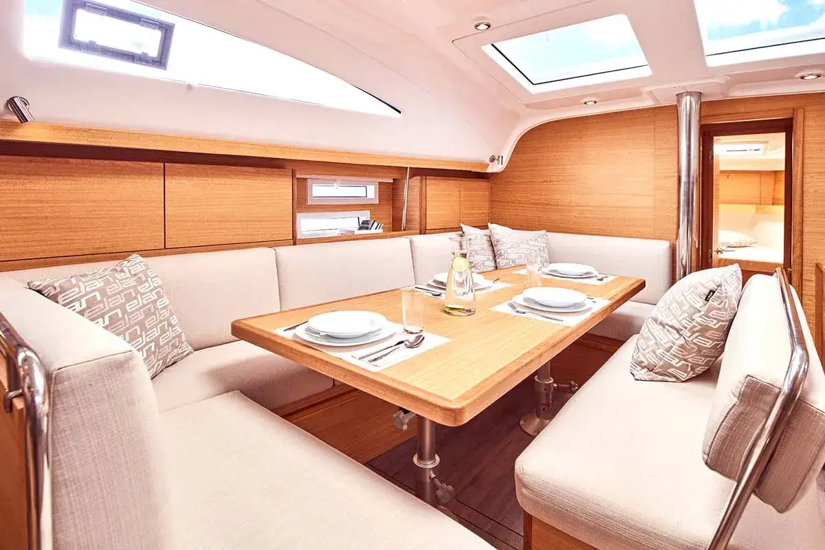 Interni accoglienti dell'Elan Impression 45.1 con tavolo da pranzo in legno, divanetti imbottiti e oblò sul soffitto.