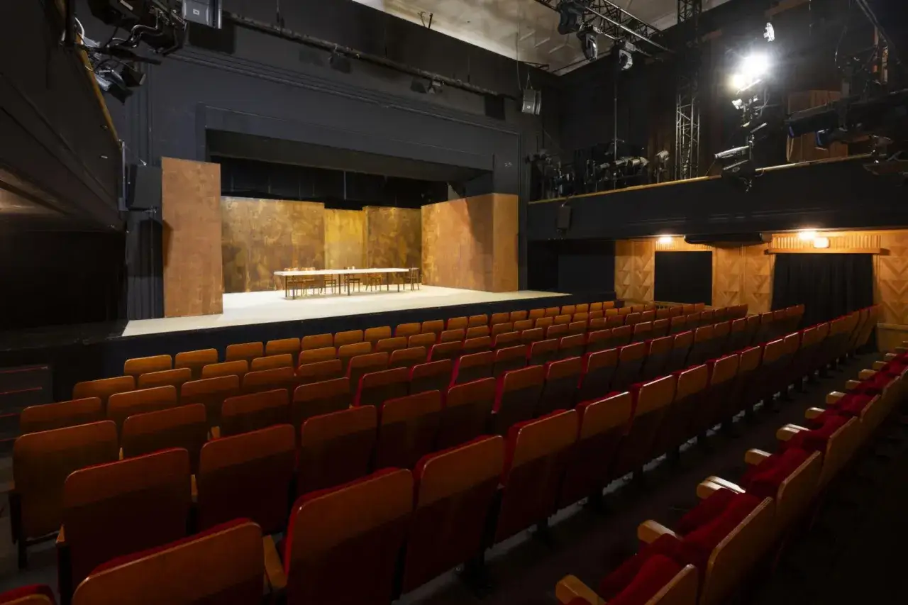 Pusta sala widowni i scena z długim stołem i krzesłami w Teatrze im. Jaracza w Warszawie.