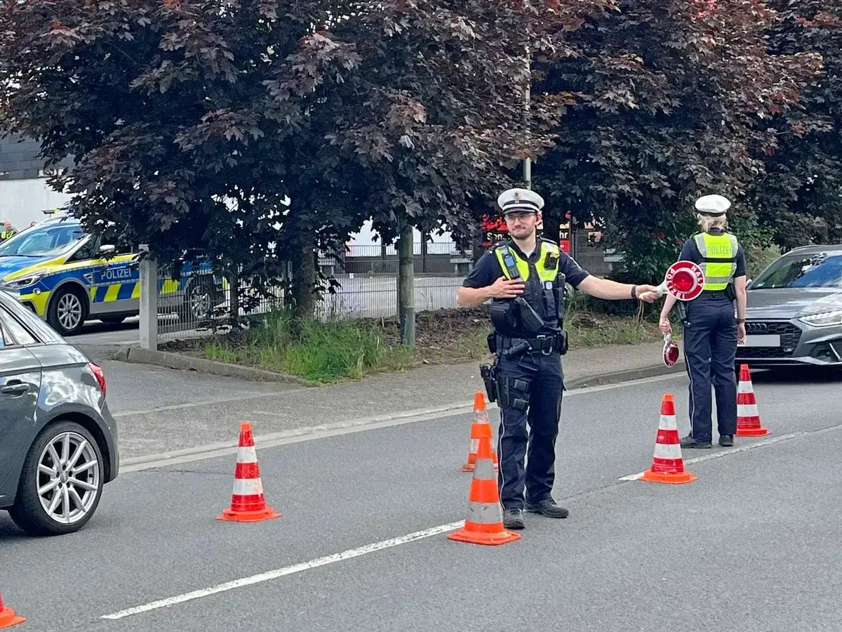 Polizei stoppt Verkehr. Ein Beamter mit Kelle und ein Kollege mit Stoppschild regeln den Verkehr. Möglicherweise Kontrolle auf cannabis am steuer.