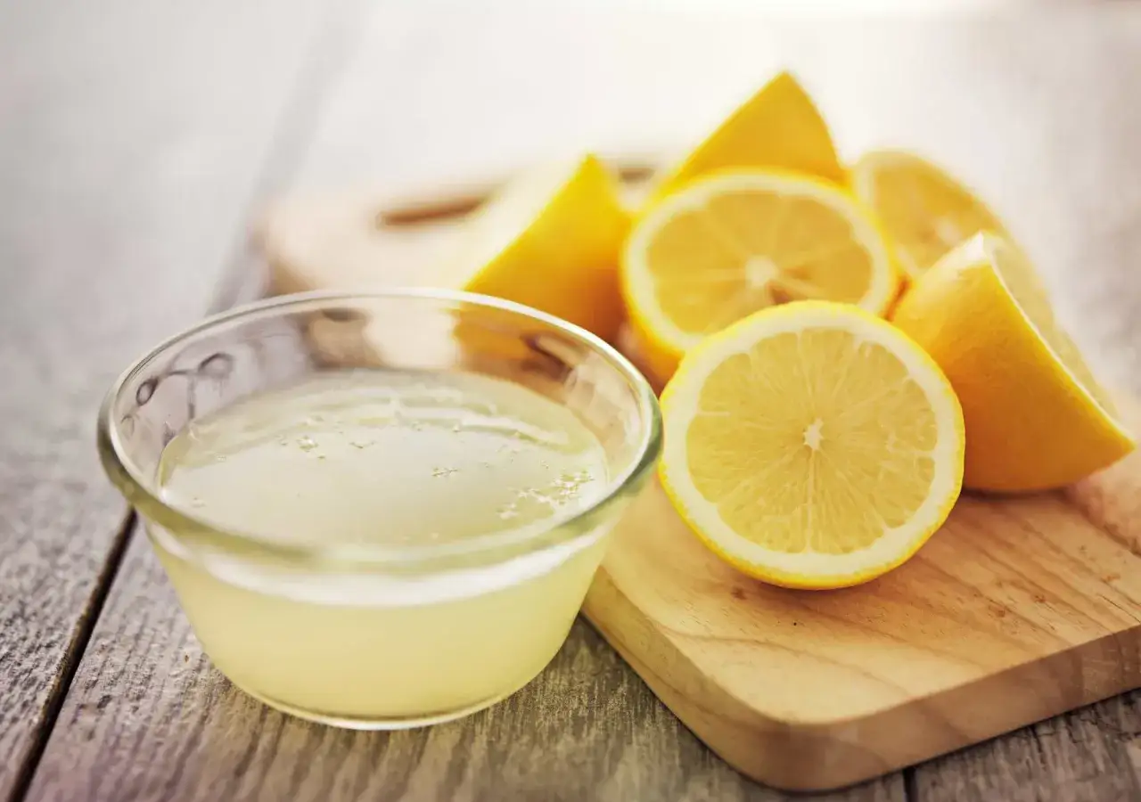 Frischer Zitronensaft in einer Schale, daneben Zitronenspalten. Ein nat&uuml;rliches Hausmittel zur Porenreinigung.