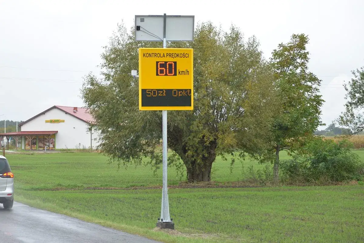 Tablica informuje o kontroli prędkości: 60 km/h, 50 zł opłaty. To przypomnienie o taryfikatorze punktów karnych.