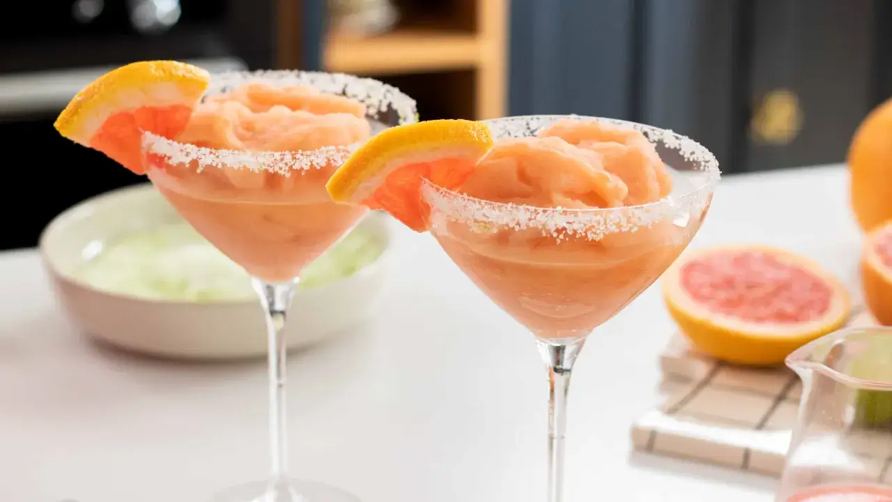 Deux verres de cocktail estival glac&eacute; au pamplemousse, bord&eacute;s de sucre et garnis d'une tranche de fruit.