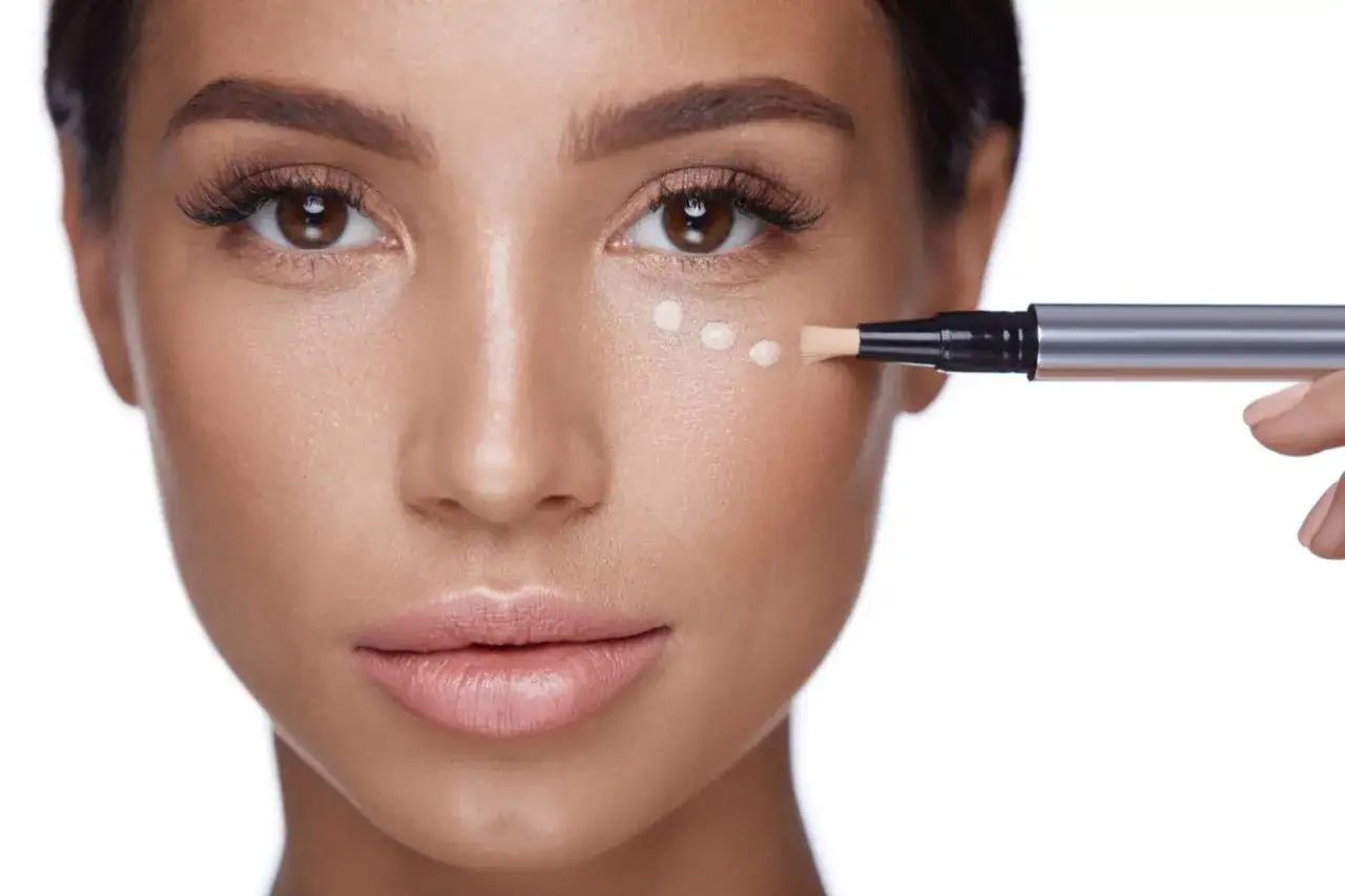 Application de correcteur pour camoufler les cernes marrons. Un stylo applicateur d&eacute;pose des points de produit sous l'&oelig;il.