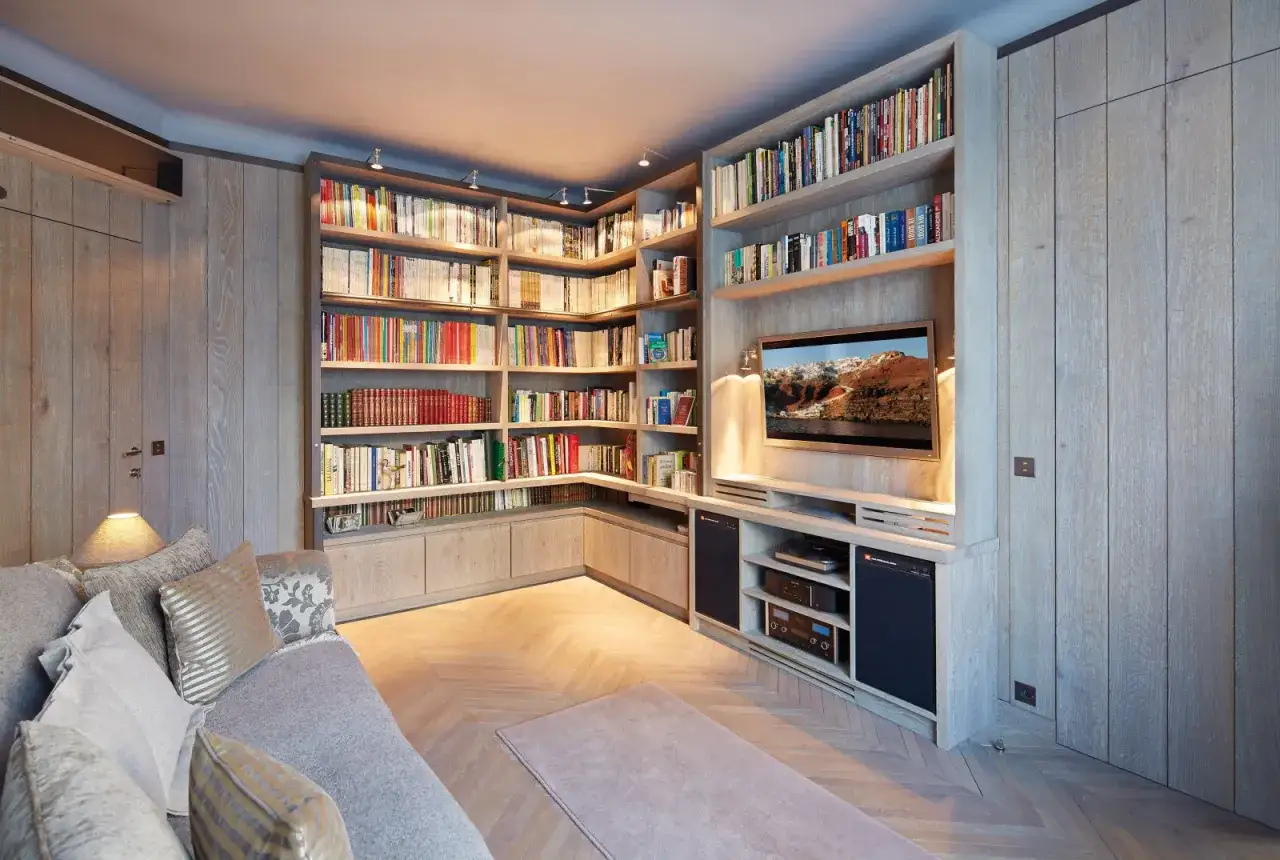 Un bel agencement bibliothèque en bois clair, avec une télévision intégrée et un canapé confortable.