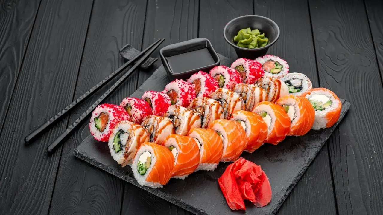 Zestaw sushi z łososiem, węgorzem i krewetkami, podany z sosem sojowym, wasabi i imbirem. Idealne z czym jeść sushi.