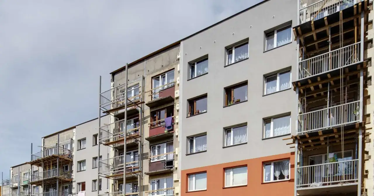 Bloki z wielkiej płyty w trakcie termomodernizacji. Widać rusztowania i nowe ocieplenie elewacji.