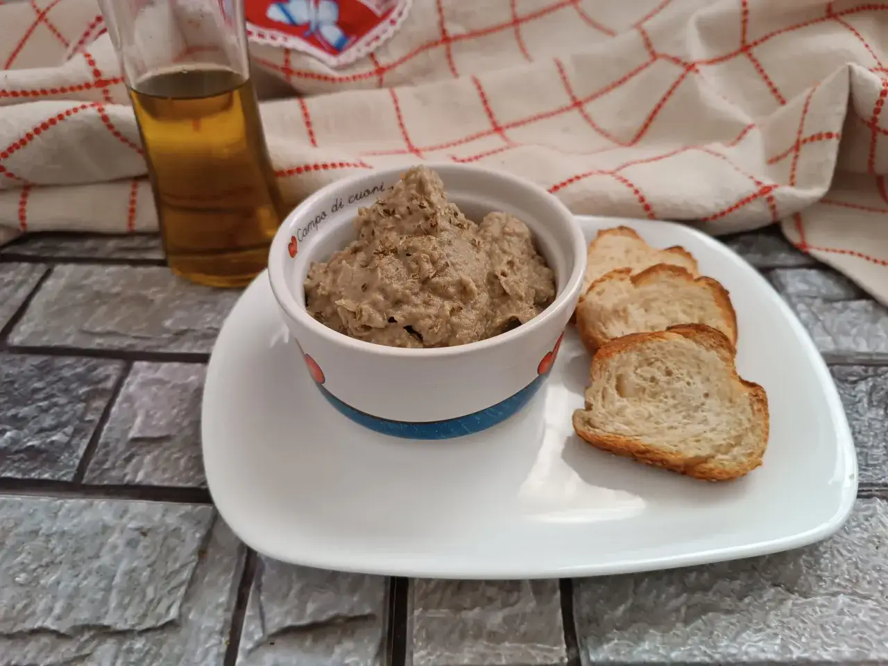 Hummus di melanzane cremoso in una ciotola, accompagnato da crostini dorati e un filo d'olio. Perfetto per un aperitivo gustoso.