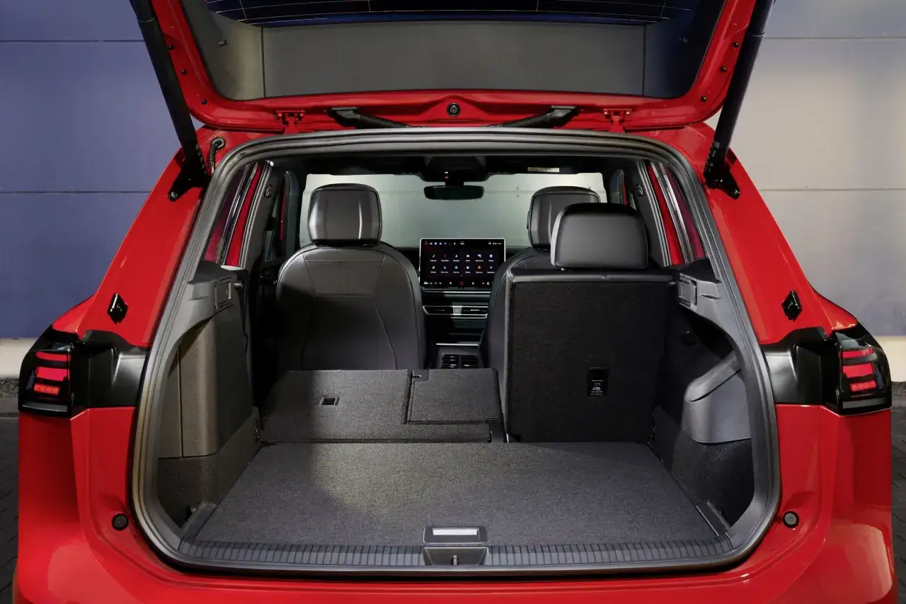 Wnętrze czerwonego Tiguan 2019 z otwartym bagażnikiem. Widoczne tylne siedzenia i duża przestrzeń bagażowa.