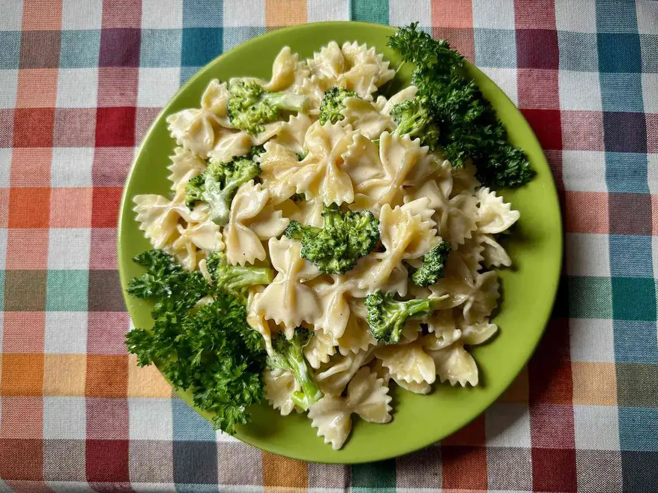 Pasta con br&oacute;coli en un plato verde, decorada con perejil fresco. Un plato sencillo y delicioso.