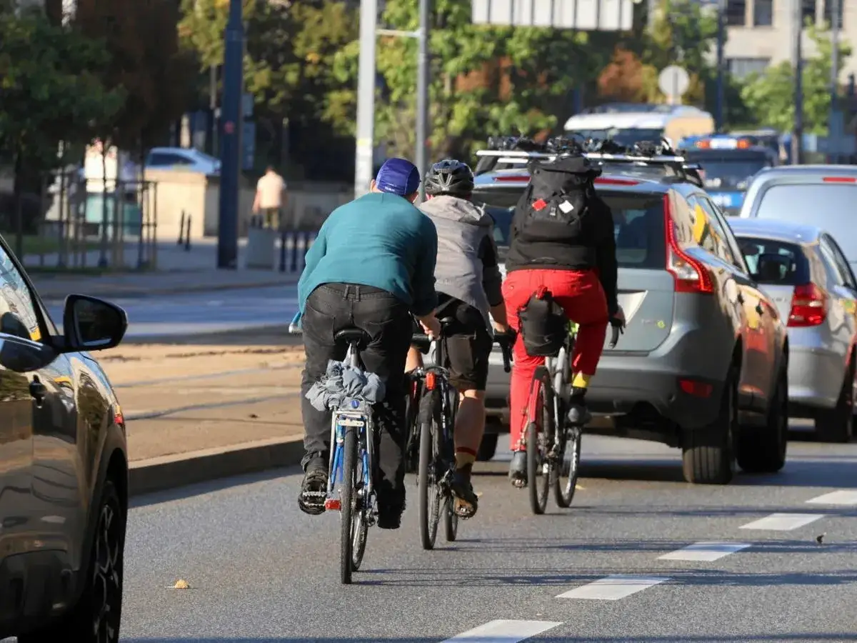 Trzech rowerzystów w ruchu miejskim. Czy można jeździć na rowerze w słuchawkach? Bezpieczeństwo przede wszystkim!