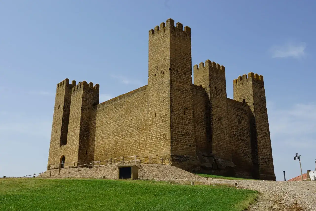 Imponente fortaleza de piedra, uno de los castillos de Arag&oacute;n, se alza majestuoso bajo un cielo azul.