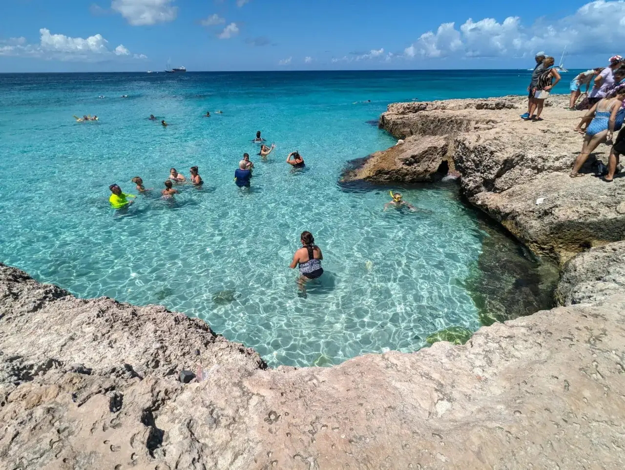 Menschen genie&szlig;en einen sonnigen Urlaub im November im kristallklaren, t&uuml;rkisfarbenen Meer, schwimmen und schnorcheln zwischen Felsen.