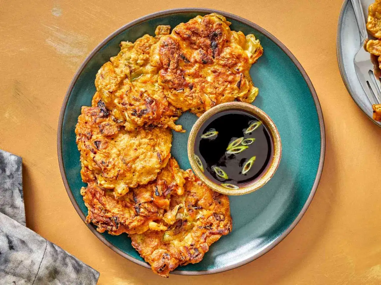Deftige Pancakes mit Zwiebeln und einer dunklen Dip-Sauce, garniert mit Fr&uuml;hlingszwiebeln.