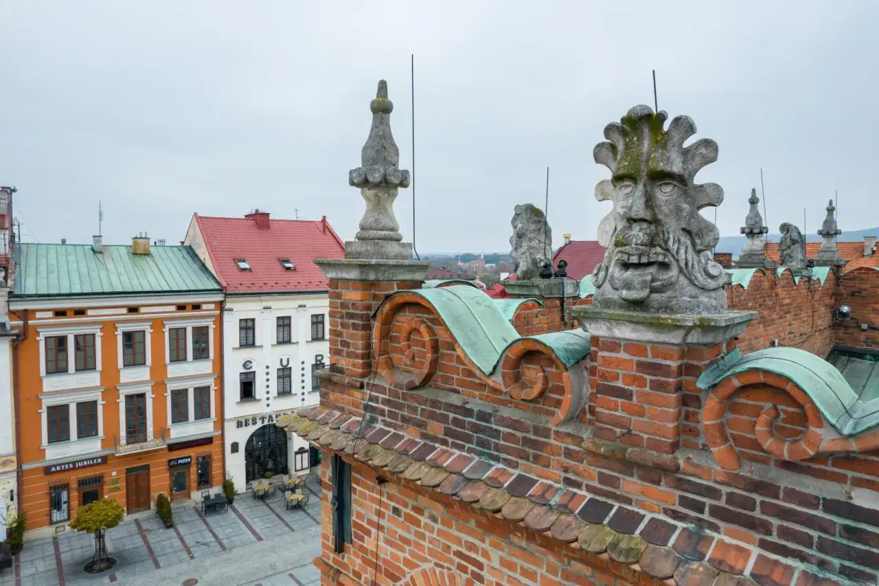 Kamienne gargulce zdobią dach kamienicy, idealne na tani wypad na weekend w Polsce. Widok na rynek i kolorowe fasady.