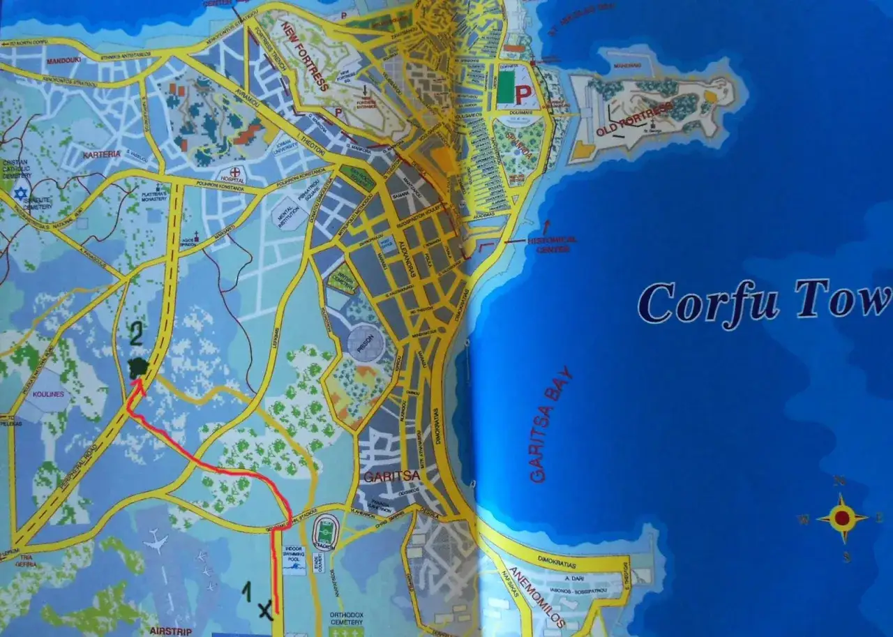 Mapa Korfu z zaznaczonymi trasami komunikacji miejskiej, w tym drogami i przystankami.